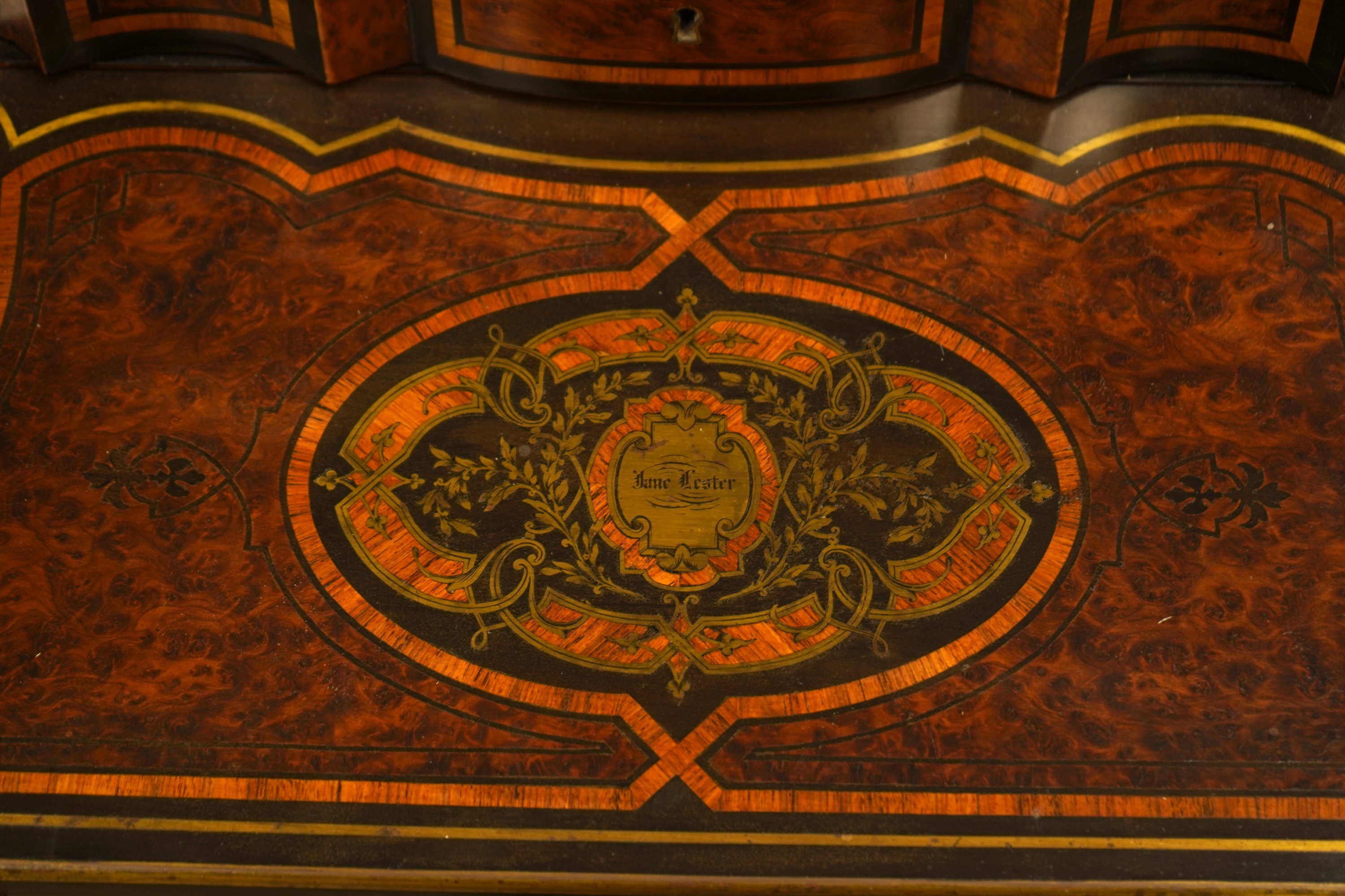 A 19th century French brass inlaid, tulip banded amboyna writing casket, the brass panel inscribed ‘Jane Lester’, 40cm wide